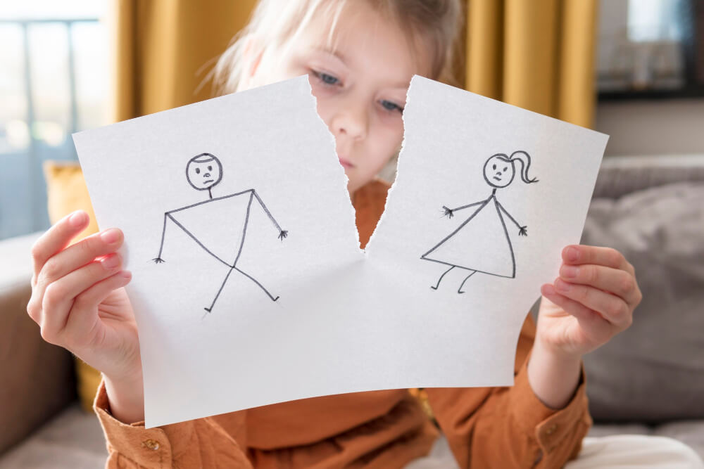 Mała dziewczynka przerywa kartkę z rysunkiem rodziców